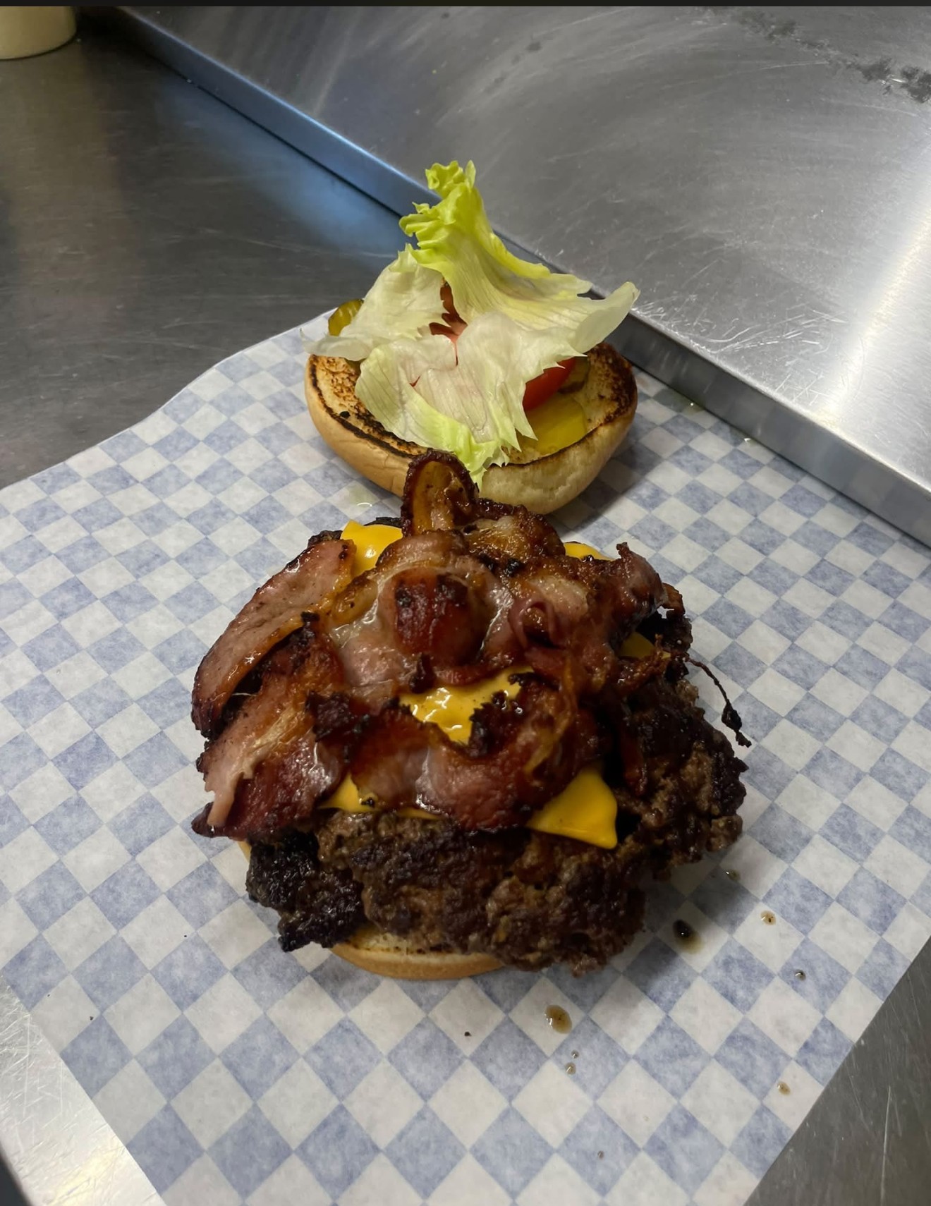 Open-faced bacon cheeseburger on checkered paper